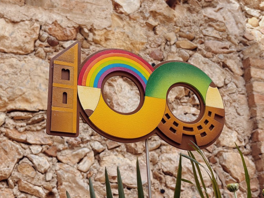 Logotip del centenari de l'Escola Modesta Pous de Vilanant retolat sobre fusta
